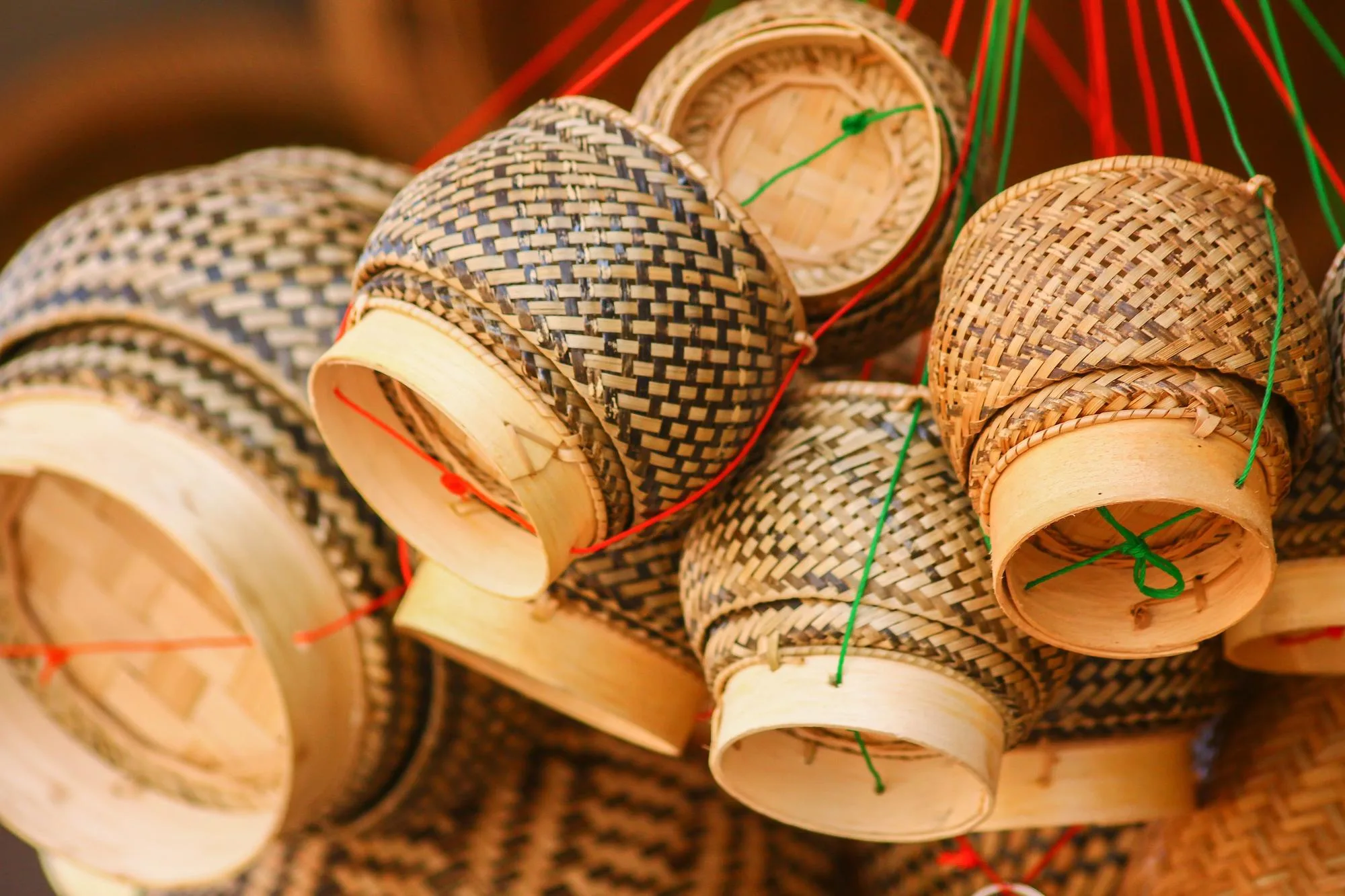 Handwoven bamboo baskets with geometric patterns hanging by colorful cord